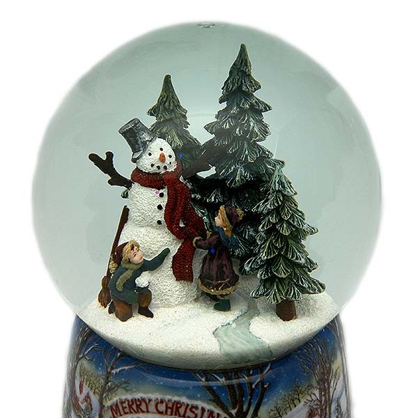 Bola de nieve navideña, en la que vemos a un niño y una niña construyendo un muñeco de nieve.