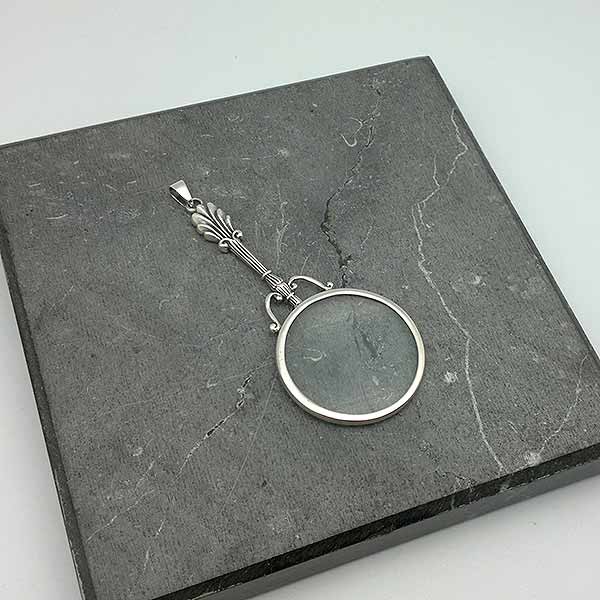 Pendant in sterling silver, shaped like a magnifying glass.
