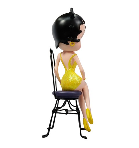 Betty boop, sentada en silla con vestido amarillo