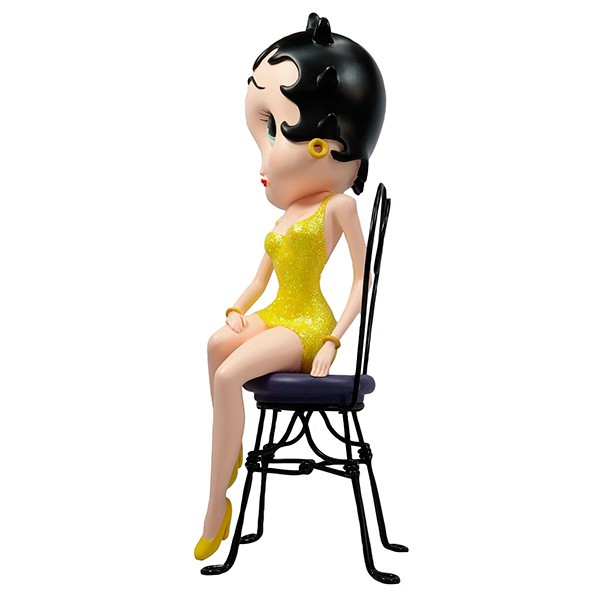 Betty boop, sentada en silla con vestido amarillo
